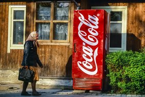 Schmuckbild: Alte Frau geht an Coca-Cola Automaten vorbei